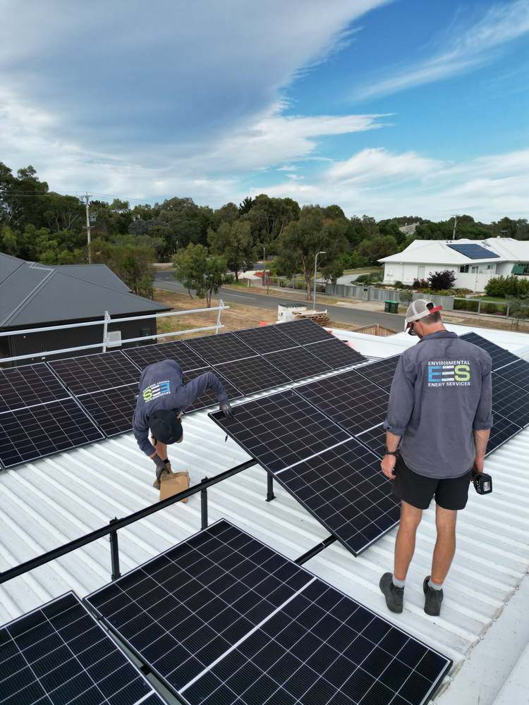 Crew laying panels on a standing seam roof